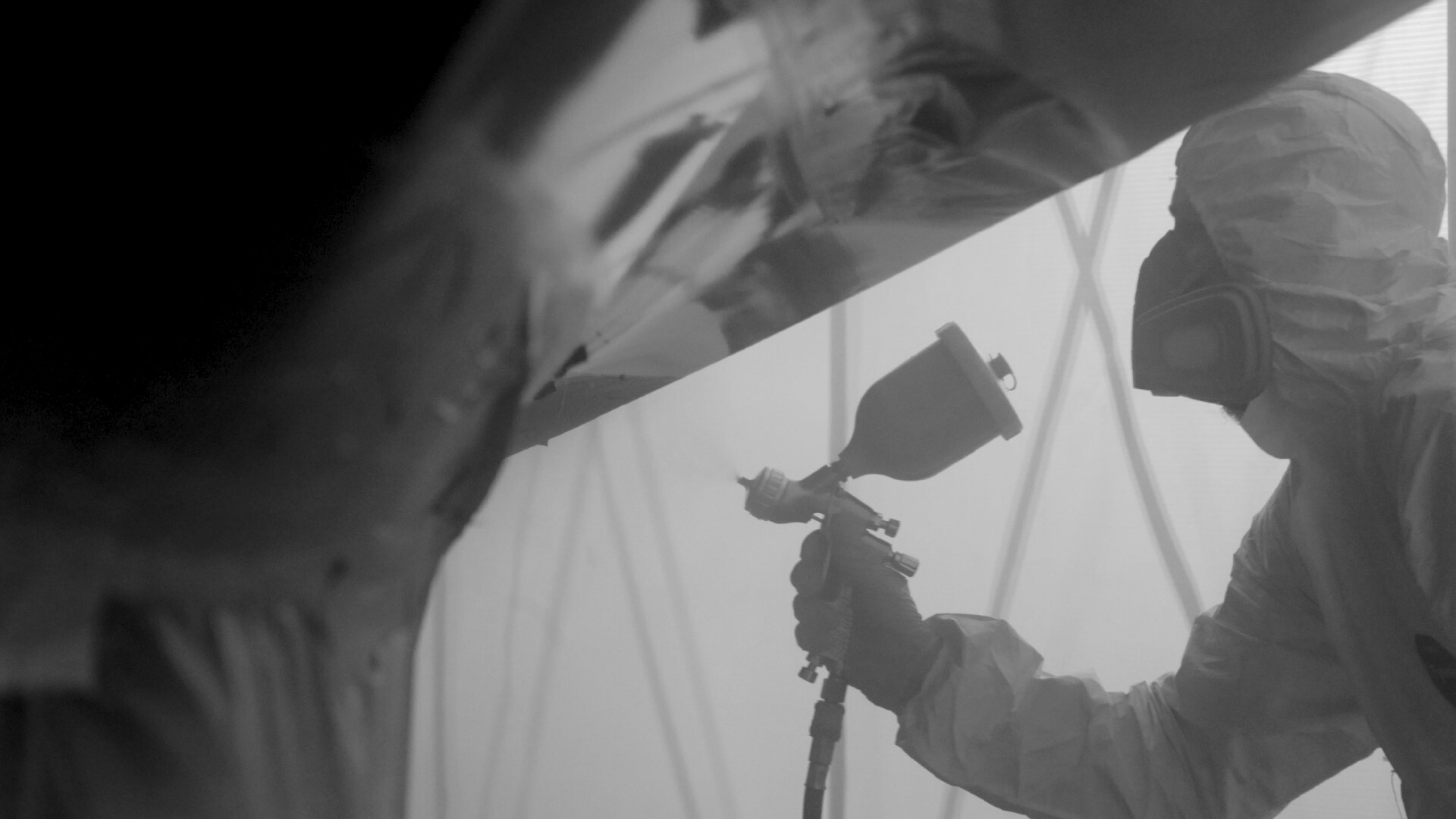 Spray operative in full protective equipment working inside a Hutchinson's retractable spray booth.