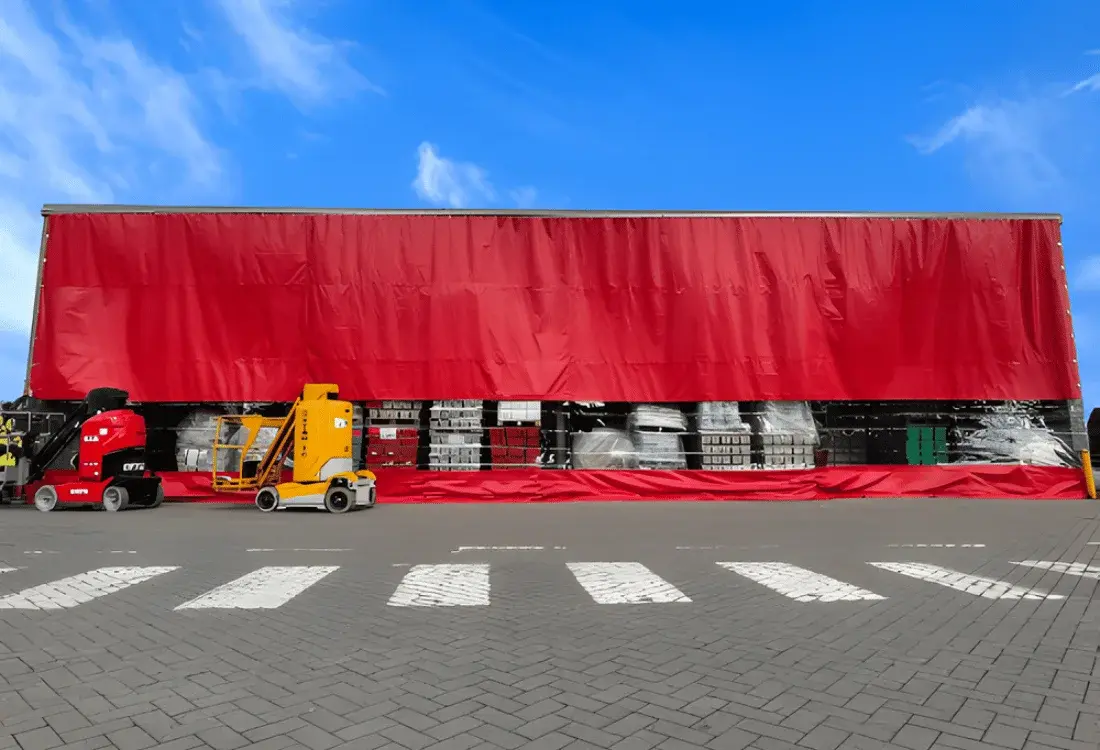 Heavy-duty red industrial warehouse curtain partition installed inside a factory workspace