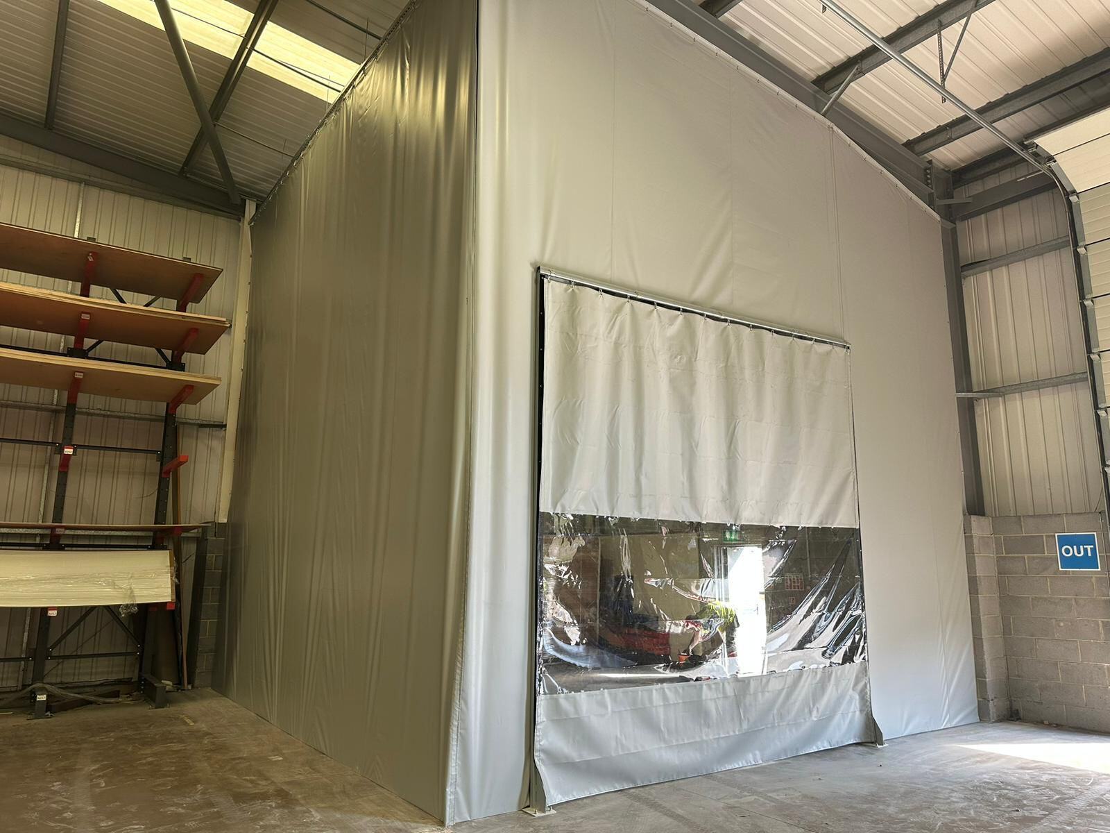 Warehouse partitions manufactured and installed in-house, creating enclosed workspace with integrated access door and clear viewing panel.